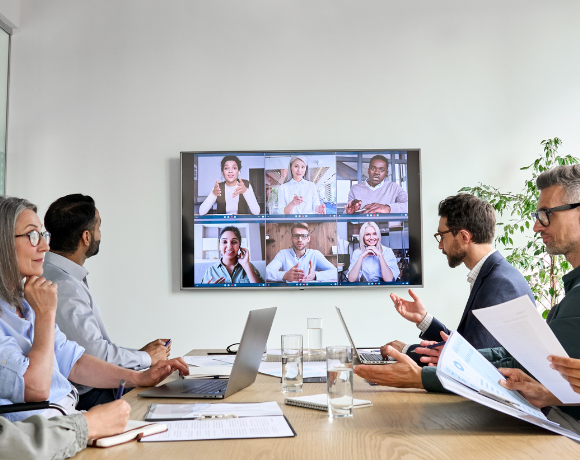 Medewerkers in een moderne hybride vergaderruimte die met één druk op de knop een meeting starten via Unite.